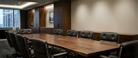 Modern corporate boardroom with long wooden conference table and black leather chairs in upscale office interior for business meetings and presentations.