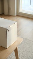 Minimalist cardboard box on wooden table in bright modern apartment interior with natural light from window for moving or storage concept.