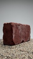 Red clay brick on gravel surface against neutral background for construction and building materials industry applications.