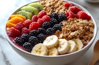 Fresh fruit and granola bowl with raspberries, blackberries, kiwi, banana slices, and apricot arranged in colorful sections with crunchy homemade granola on marble surface.
