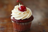 Chocolate cupcake topped with swirled vanilla buttercream frosting and garnished with bright red maraschino cherry on rustic wooden background, macro food photography.