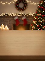 Wooden table with blurred festive background featuring decorated tree, fireplace, stockings, wreath, and twinkling lights. Perfect for holiday product displays and seasonal marketing.