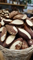 Fresh Brazil nuts sliced in half showing creamy white interior and brown shells, displayed in wicker basket at local market.