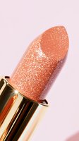Shimmering coral lipstick with glitter particles in golden tube against pink background, macro shot showing luxurious cosmetic texture and sparkle detail.