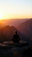 Person meditating on mountain cliff edge during golden hour sunrise with dramatic canyon landscape and warm sunlight creating peaceful silhouette for wellness content.