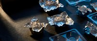 Sparkling crystal clear ice cubes scattered on dark wooden surface with dramatic lighting creating reflections and shadows for beverage photography.