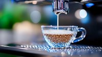 Fresh espresso pouring into glass cup with bubbles and crema, illuminated by blue bokeh lights against dark background, macro photography closeup.