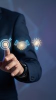 Businessman in dark suit pointing at glowing digital icons representing target, partnership, and innovation for business strategy and success concepts.