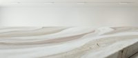 Young adult male with light skin tone, wearing casual attire, standing in minimalist concrete architectural space with curved white and beige surfaces, suitable for modern design and lifestyle content.