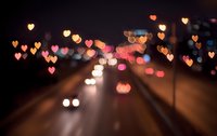 Romantic heart-shaped bokeh lights creating dreamy atmosphere over blurred city street at night for Valentine's Day celebrations and love concepts.
