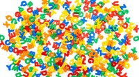 Colorful plastic alphabet letters scattered randomly on white background, educational learning materials for children's literacy development and spelling games.