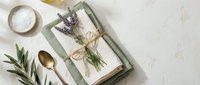 Spa wellness flat lay with lavender, sea salt, wooden spoon and natural linen napkin on white textured background for relaxation and self-care concepts.