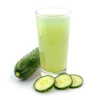 Fresh cucumber juice in glass with whole cucumber and slices on white background, healthy detox drink for wellness and nutrition.