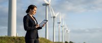 Professional businesswoman using tablet at wind farm for renewable energy project management and sustainable technology development.