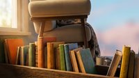 Vintage leather backpack with colorful books on wooden shelf near window with soft natural light creating cozy reading atmosphere for education concepts.