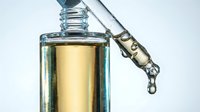 Clear glass dropper bottle filled with golden yellow liquid serum or oil, isolated on white background, ready for cosmetics, skincare, wellness product packaging design.