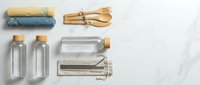Rolled natural fabrics, wooden utensils, and glass bottles arranged on marble surface for sustainable lifestyle, eco-friendly living, zero waste, and organic product concepts.
