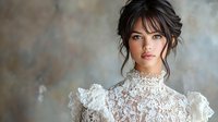 Young Asian woman in vintage white lace dress with high collar and upswept dark hair against textured background, romantic bridal portrait in soft natural lighting.