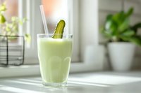 Fresh cucumber smoothie in glass with straw and cucumber slice garnish on bright windowsill, perfect for healthy lifestyle content.
