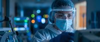 Healthcare worker in protective equipment conducting medical research in modern laboratory with advanced technology and colorful background lighting.