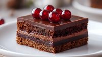 Decadent chocolate layer cake slice with dark ganache frosting and fresh red cherries on top, served on white plate. Rich dessert with multiple textures.