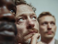 Close-up of diverse business team looking up with contemplative expressions, showcasing collaboration and forward thinking in corporate environment.