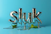Metallic silver balloon letters spelling "Sluk" with dripping effect on turquoise background, green leaves adding natural contrast.