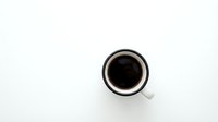 White coffee cup with black coffee viewed from above on clean white background for minimalist design projects.