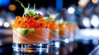 Fresh salmon appetizer with red caviar and avocado served in elegant glass shots on dark background with bokeh lights, luxury restaurant presentation.