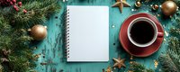 Empty notebook with coffee cup on turquoise wooden background decorated with golden Christmas ornaments, fir branches and berries for holiday planning.