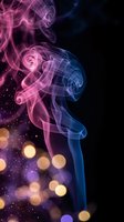 Colorful smoke swirls in pink and blue hues with golden bokeh lights creating mystical atmosphere on black background for creative design projects.