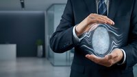 Businessman in dark suit holding digital fingerprint scan between hands in modern office environment, representing biometric security and identity verification technology.
