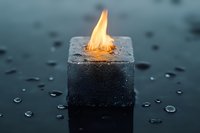 Burning ice cube with orange flame on wet surface with water droplets creates surreal contrast between fire and ice elements for creative concepts.