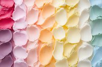 Colorful pastel buttercream frosting swirls arranged in rainbow pattern, showing smooth textured peaks and valleys. Macro food photography highlights soft gradient colors.