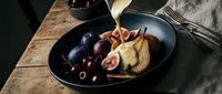 Gourmet cheese and fresh figs with grapes on dark plate, elegant food styling for culinary photography and restaurant menu design.