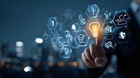 Businessman touching virtual light bulb icon among digital hexagon symbols, representing innovation and technology solutions against city skyline.