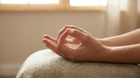 Elderly woman's hands resting on lap in peaceful meditation pose, warm natural light, mindfulness and relaxation concept for wellness and mental health content.