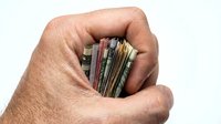 Closeup of male hand holding stack of colorful credit cards and cash money, isolated on white background for financial, banking, payment and wealth concepts.