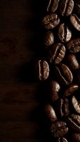 Roasted coffee beans arranged on dark wooden surface with dramatic side lighting, creating rich shadows and highlights. Perfect for beverage, café, and food industry designs.