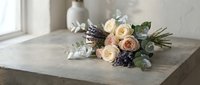 Elegant bridal bouquet with cream roses and eucalyptus on rustic wooden table by window, romantic wedding floral arrangement for ceremony decoration.