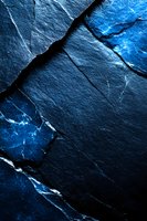 Dramatic dark stone texture with glowing blue cracks and veins creating abstract pattern on black slate surface, suitable for luxury design backgrounds.