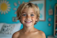 Happy young boy with blonde wavy hair and bright smile in colorful classroom setting. Portrait suitable for educational materials, childcare, parenting, and learning content.