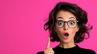 Young Caucasian woman with glasses showing surprised expression, raised finger against vibrant pink background. Emotional portrait concept for advertising and design.