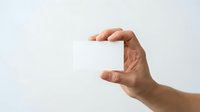 Hand of a man with medium skin tone holding a blank white card or paper, suitable for business cards, promotional materials, and advertising mockups.