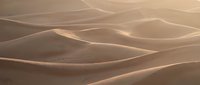 Soft golden sand dunes stretch across a vast desert landscape, bathed in warm sunlight, creating smooth flowing curves and shadows.