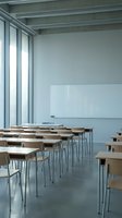 Modern minimalist classroom with wooden desks and chairs arranged in rows, featuring large windows and whiteboard for educational presentations.