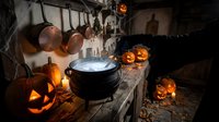 Witch's cauldron with glowing potion surrounded by carved jack-o'-lanterns, hanging herbs, copper pots, and mystical decorations in dark atmospheric setting for Halloween themes.