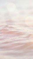 Soft pink ocean waves with dreamy pastel sky creating serene coastal atmosphere for wellness and meditation backgrounds.