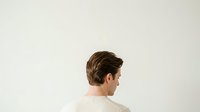 Young man with brown hair in profile view wearing a beige sweater, isolated on white background for design and commercial use.