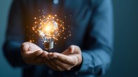 Glowing light bulb floating above businessman hands with luminous network connections, representing innovation and creative business solutions.
